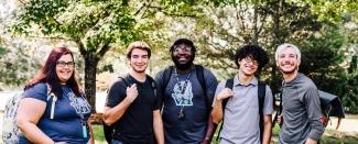 Group of students wearing backpacks and smiling at the camera